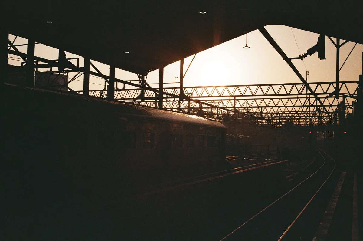 An underexposed frame: a dark train platform silhouette against a bright sky at sunrise